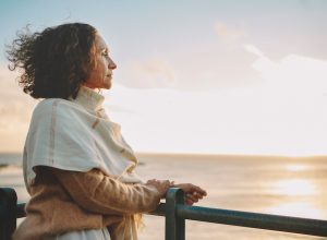 Mature woman watching the sunset over the ocean