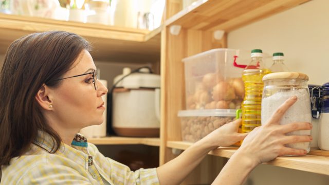 A woman checking her pantry and looking at a jar