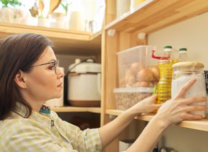A woman checking her pantry and looking at a jar