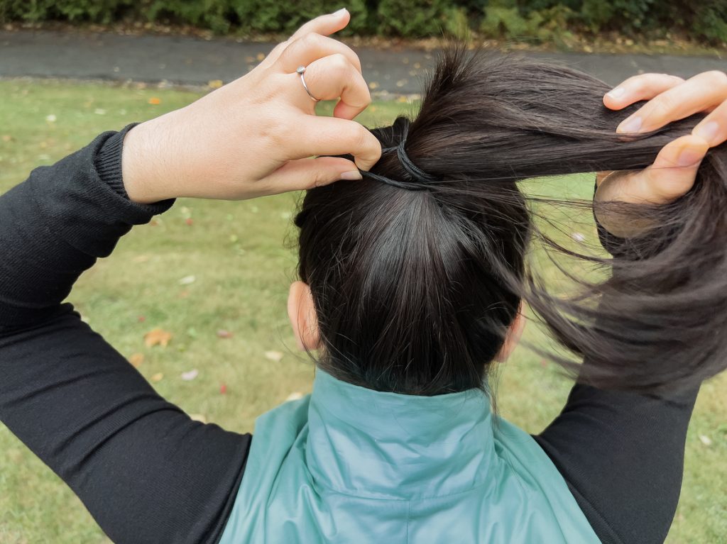 A close up of a woman tying a hair elastic into her hair