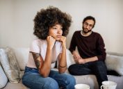 couple in living room drinking coffee or tea and expressing negative emotions