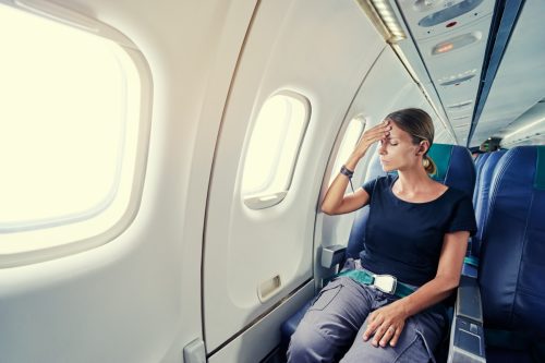 woman demonstrating a fear of flying while seated on an airplane