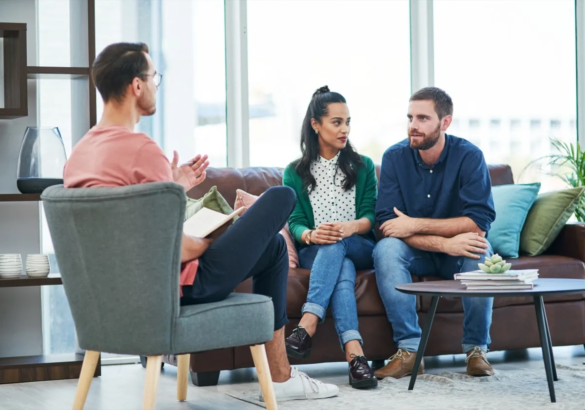 Couple sitting on a couch together in the office of a male couples counselor