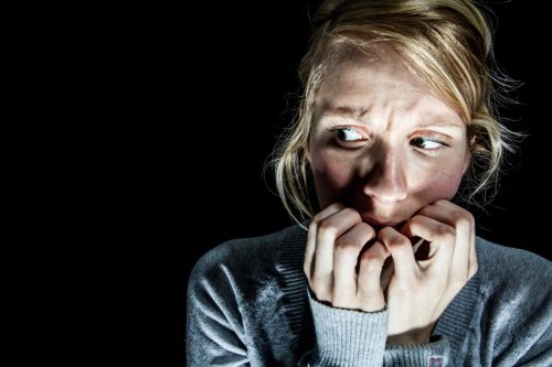 image of a woman over a black background looking scared