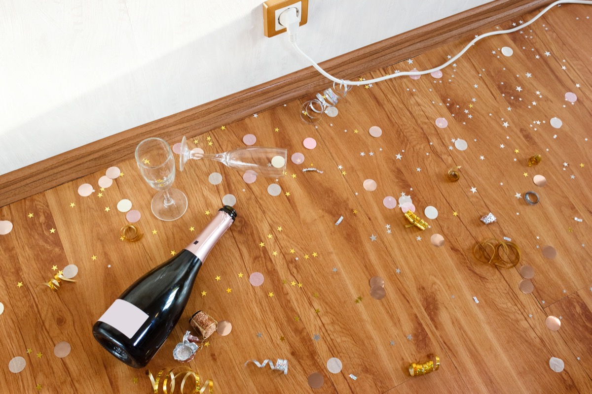 Early morning after the party. Champagne bottle and empty glasses on the floor with confetti and serpentine.