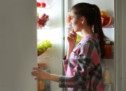 Young woman looking into fridge at night