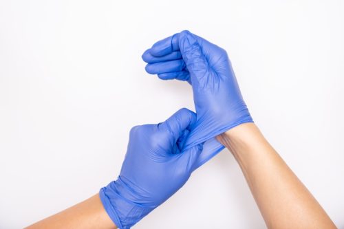 Hands pulling on blue protective gloves