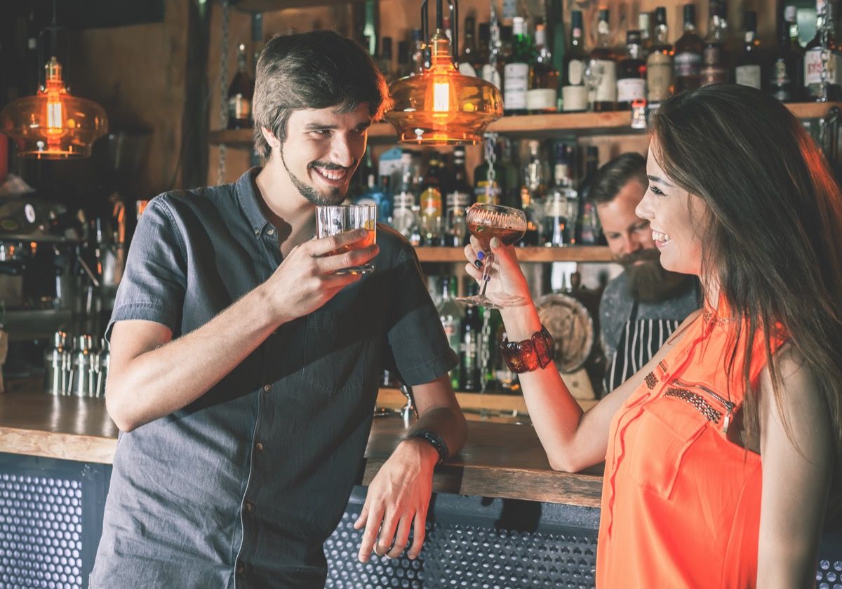 man using a cheesy pickup line to flirt with a woman at the bar