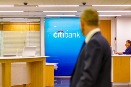 London, UK - May 15, 2017 - Citibank sign displayed at a branch in Canary Wharf with people passing by in the foreground
