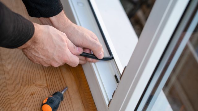 Close up of a man's hands adding weather-proofing strips to window