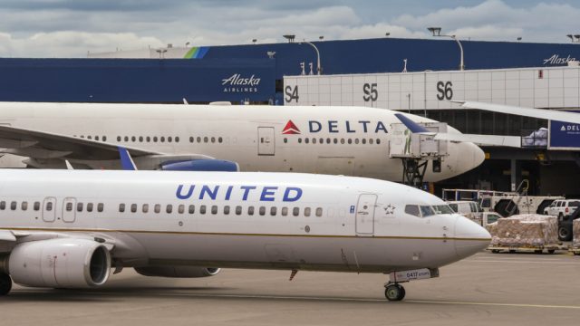 A Delta plane and United plane sitting next to each other on a runway at an airport