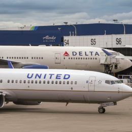 A Delta plane and United plane sitting next to each other on a runway at an airport