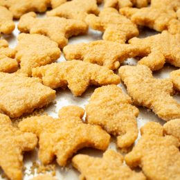 A view of a baking tray of dinosaur chicken nuggets.