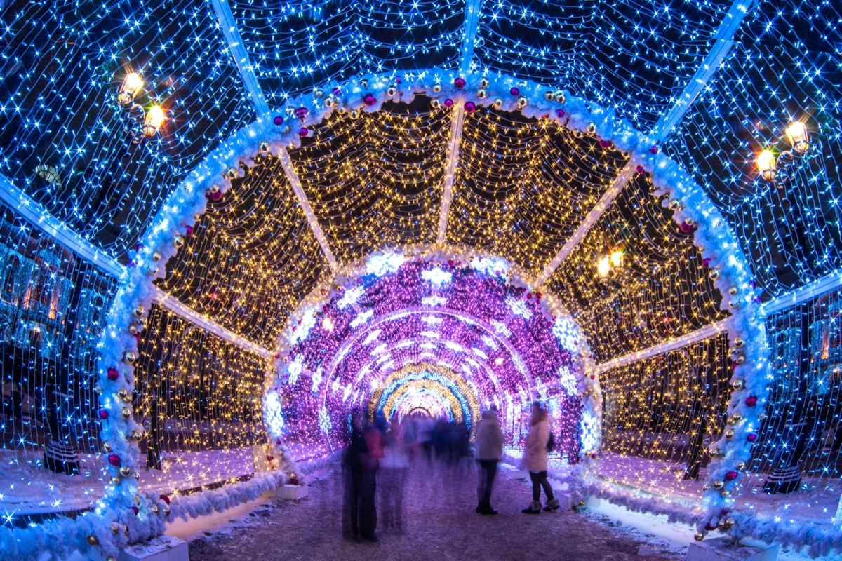 Blurred people walking through holiday light tunnel