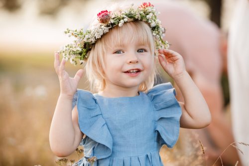 little girl is wearing a flower wreath on her head 