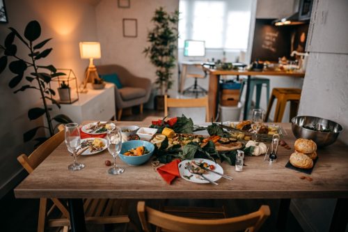 Food and drinks served on table with empty chairs at home