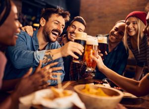 group of friends drinking beer together at a bar while asking truth or drink questions