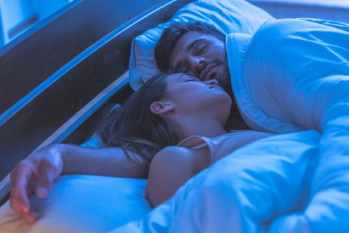 man and woman cuddling in bed at night