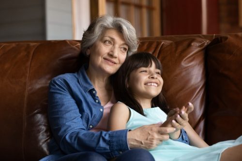 Happy grandmother hugging granddaughter on couch