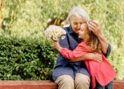 grandmother and grandaughter hugging on a park bench