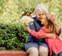 grandmother and grandaughter hugging on a park bench