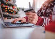 Women wearing red sweater shopping online and using credit card at home office
