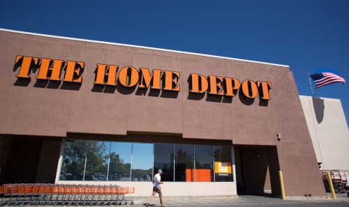 Santa Fe, NM: A man is about to enter The Home Depot near a line of orange shopping carts. The store is constructed in the Pueblo architectural style.