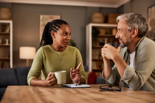 man and woman drinking coffee and talking at the kitchen table