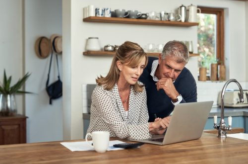 A senior couple planning their finance and paying bills while using a laptop at home. 