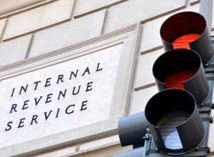 A sign outside of the IRS headquarters next to a red stoplight that reads Internal Revenue Service