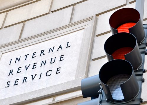 A sign outside of the IRS headquarters next to a red stoplight that reads Internal Revenue Service