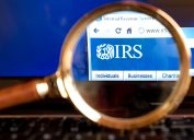 A close up of a magnifying looking at the IRS logo on the agency's website