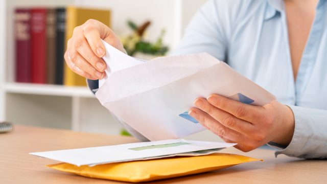 A close up of a person putting a letter or check into an envelope