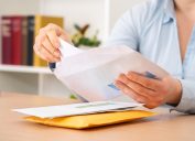 A close up of a person putting a letter or check into an envelope