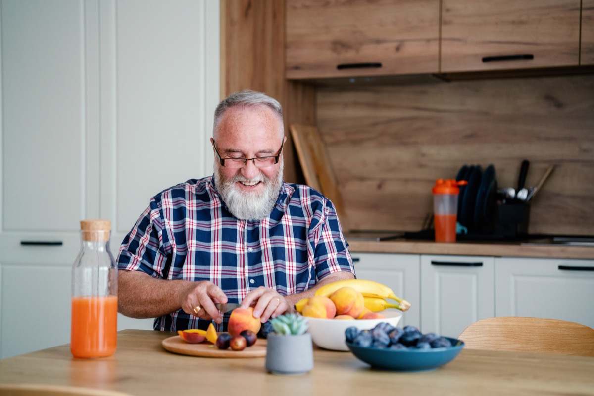 Happy mature bearded man eating healthy food at home