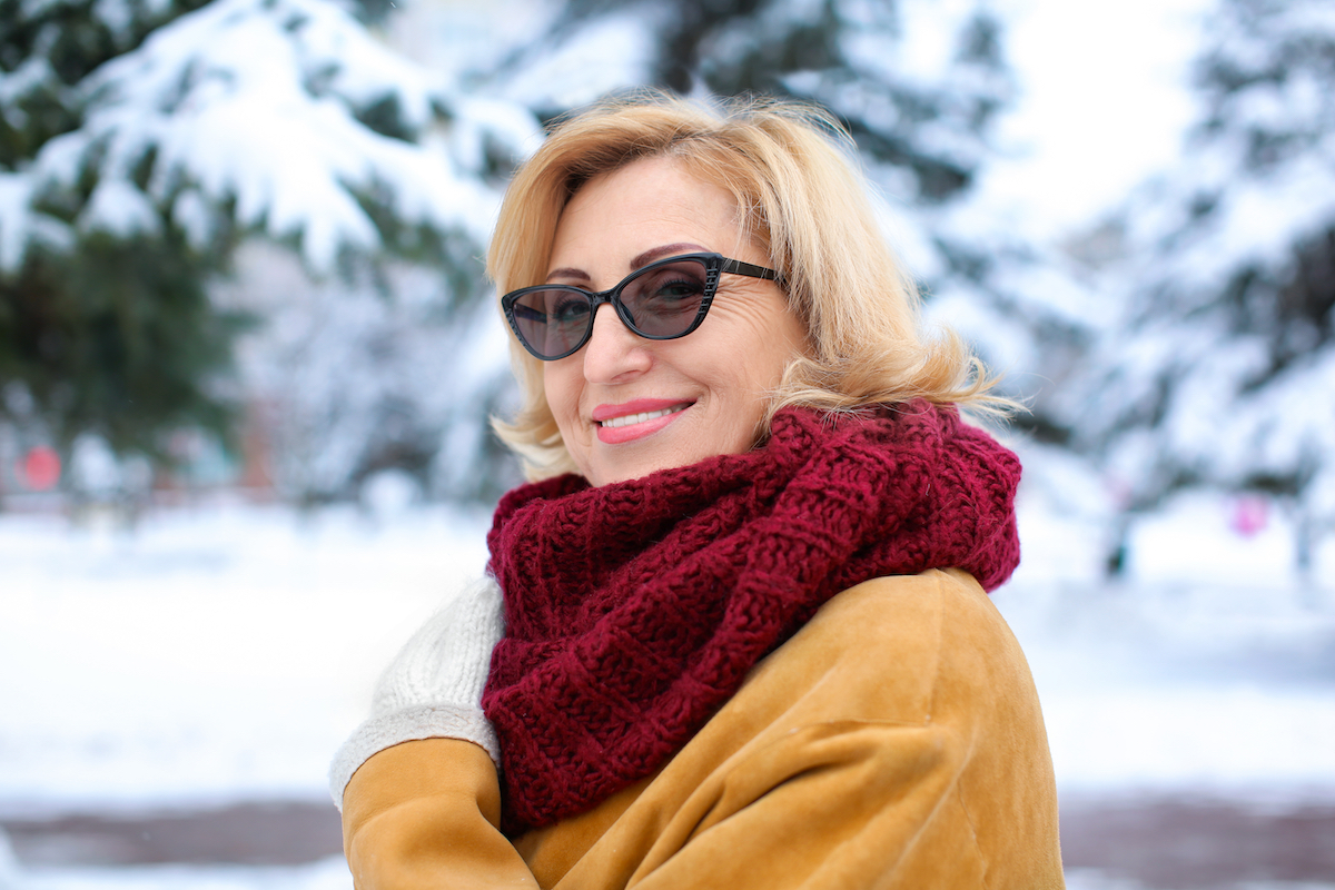 Portrait of happy mature woman in snowy park on winter vacation