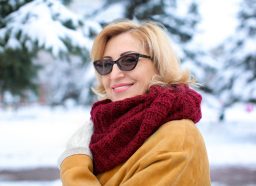 Portrait of happy mature woman in snowy park on winter vacation
