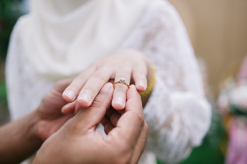 Close up on man putting wedding ring on woman's finger