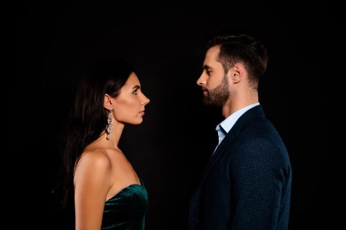 well-dressed man and woman facing off against a black background