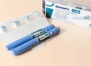 Two Ozempic pens next to their box and dose cartridges