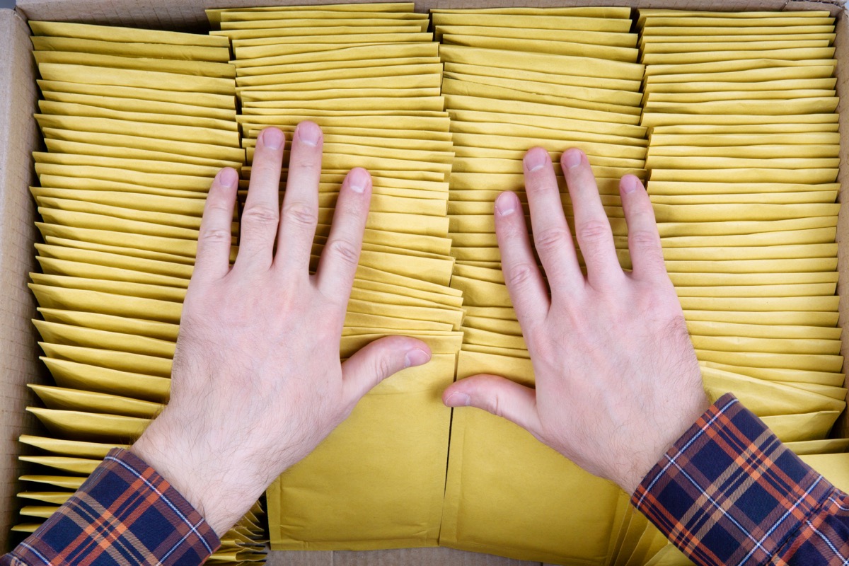 Man's hands sorting through padded envelopes