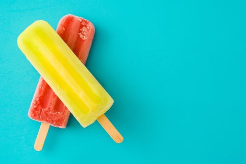 Strawberry popsicle and lemon popsicle on blue background