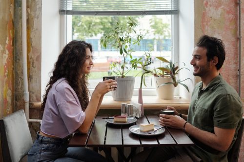 young man and woman seated at a cafe talking