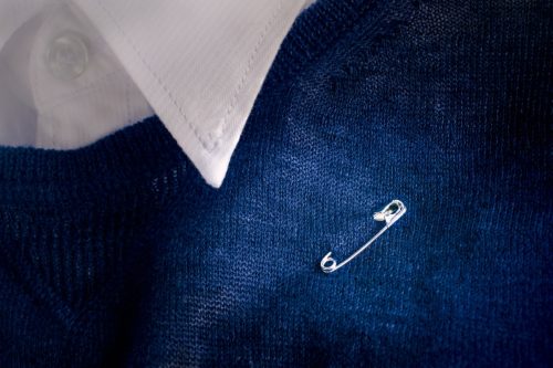 Safety pin clasp on blue sweater.