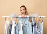 Stylist woman leaning on clothing rack with capsule wardrobe