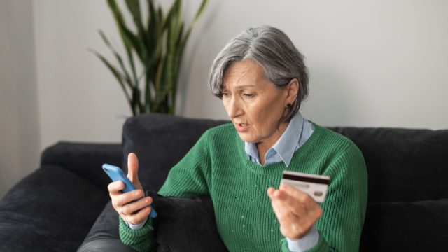 middle-aged woman surprised and concerned looking at bank account