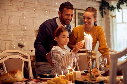 man woman and little girl lighting candles for Hanukkah