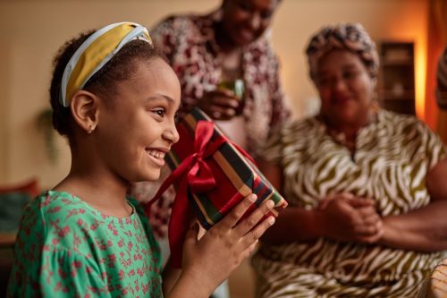 excited girl opening gifts for kwanzaa