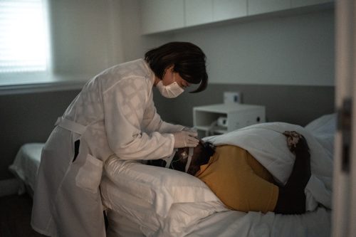 Doctor placing electrodes on patient's head for a medical exam - wearing protective face mask