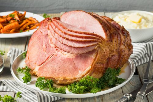 Homemade Glazed Spiral Cut Ham on set table with Carrots and Potatoes
